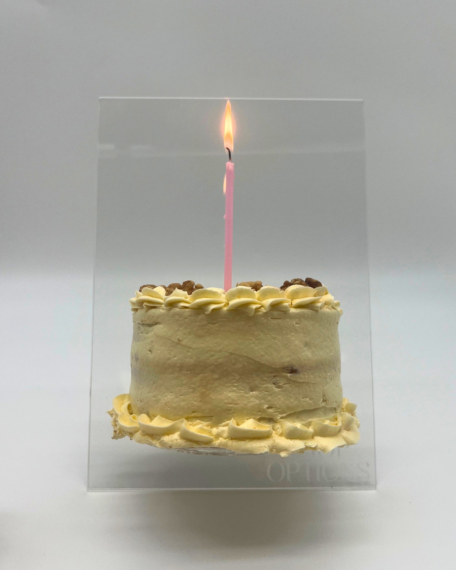 Clear acrylic cake easel stand for displaying decorated cakes, shown holding an 8-inch cake.