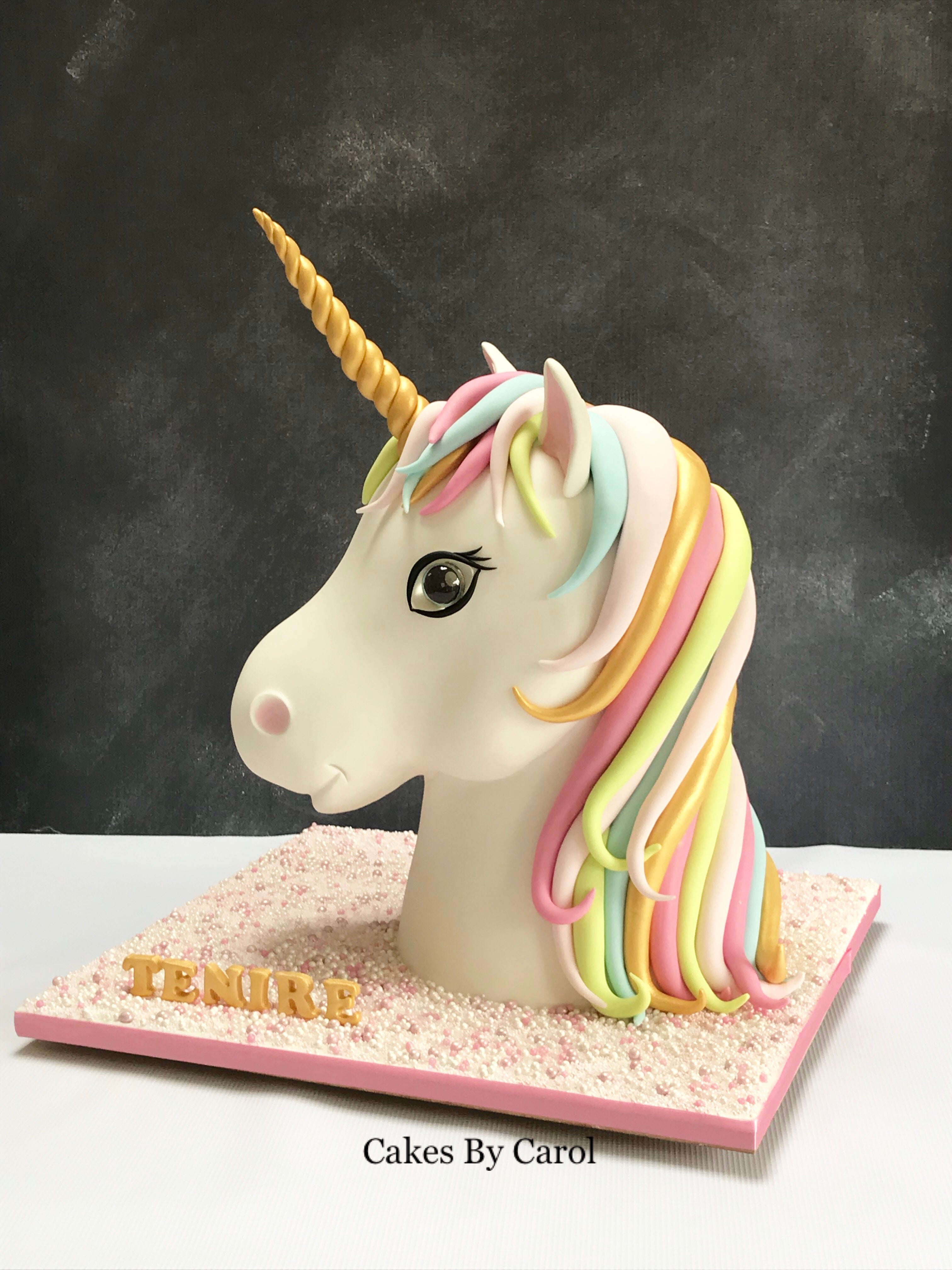 Unicorn cake with colorful mane on a stand against a dark background